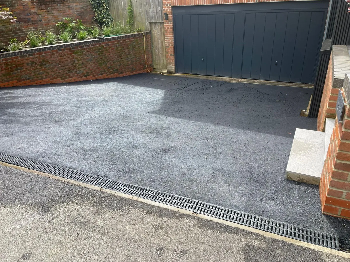 A new tarmac driveway laid up to the garage, with a drainage channel along the edge