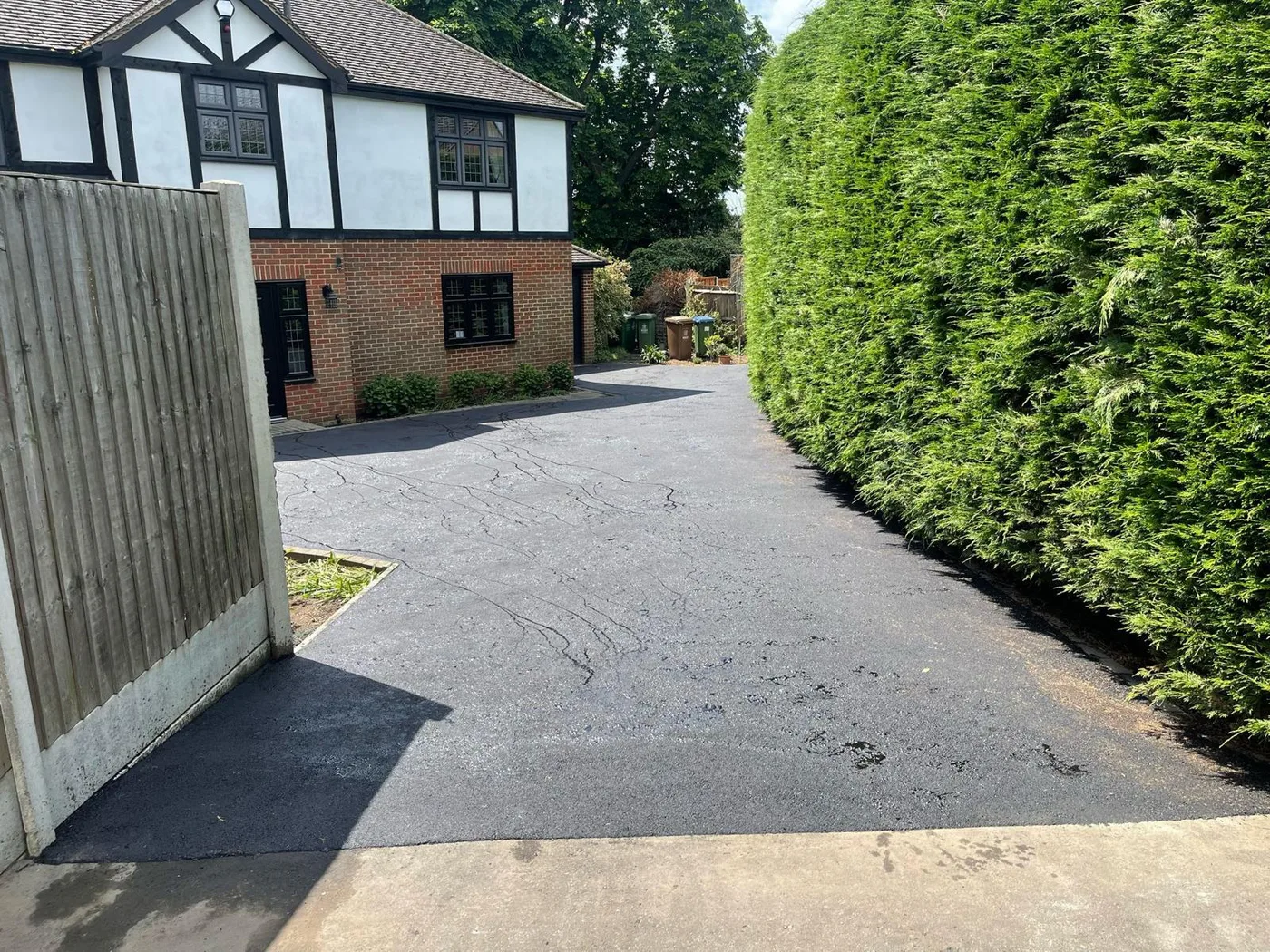 A resurfaced driveway running alongside a mature hedge