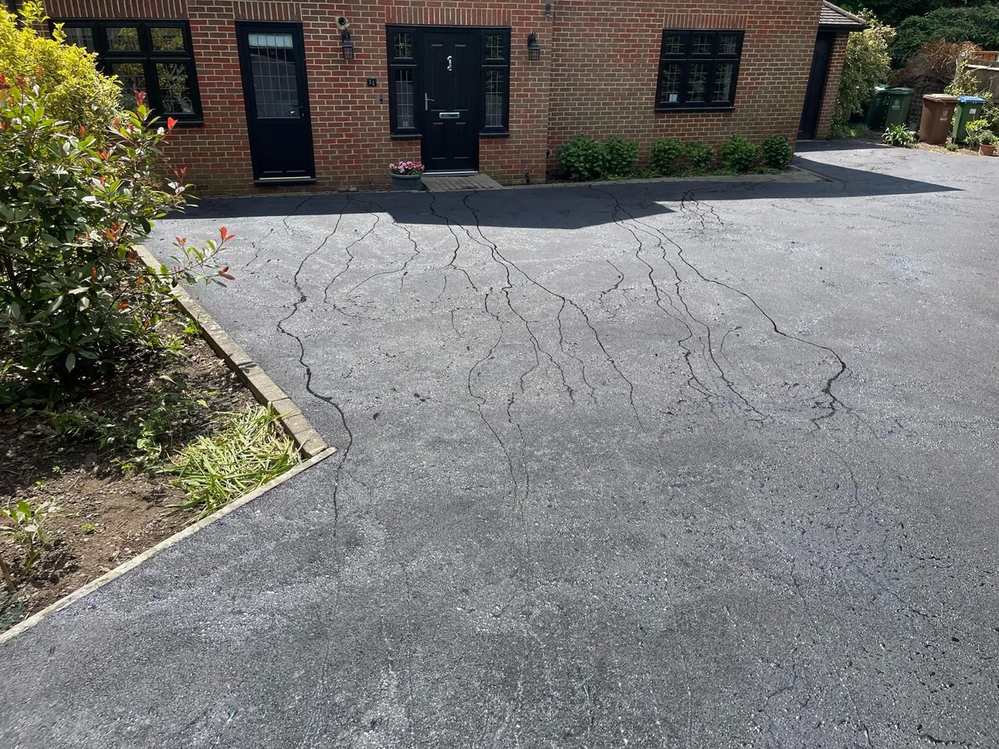 A worn residential driveway showing surface cracking, before resurfacing