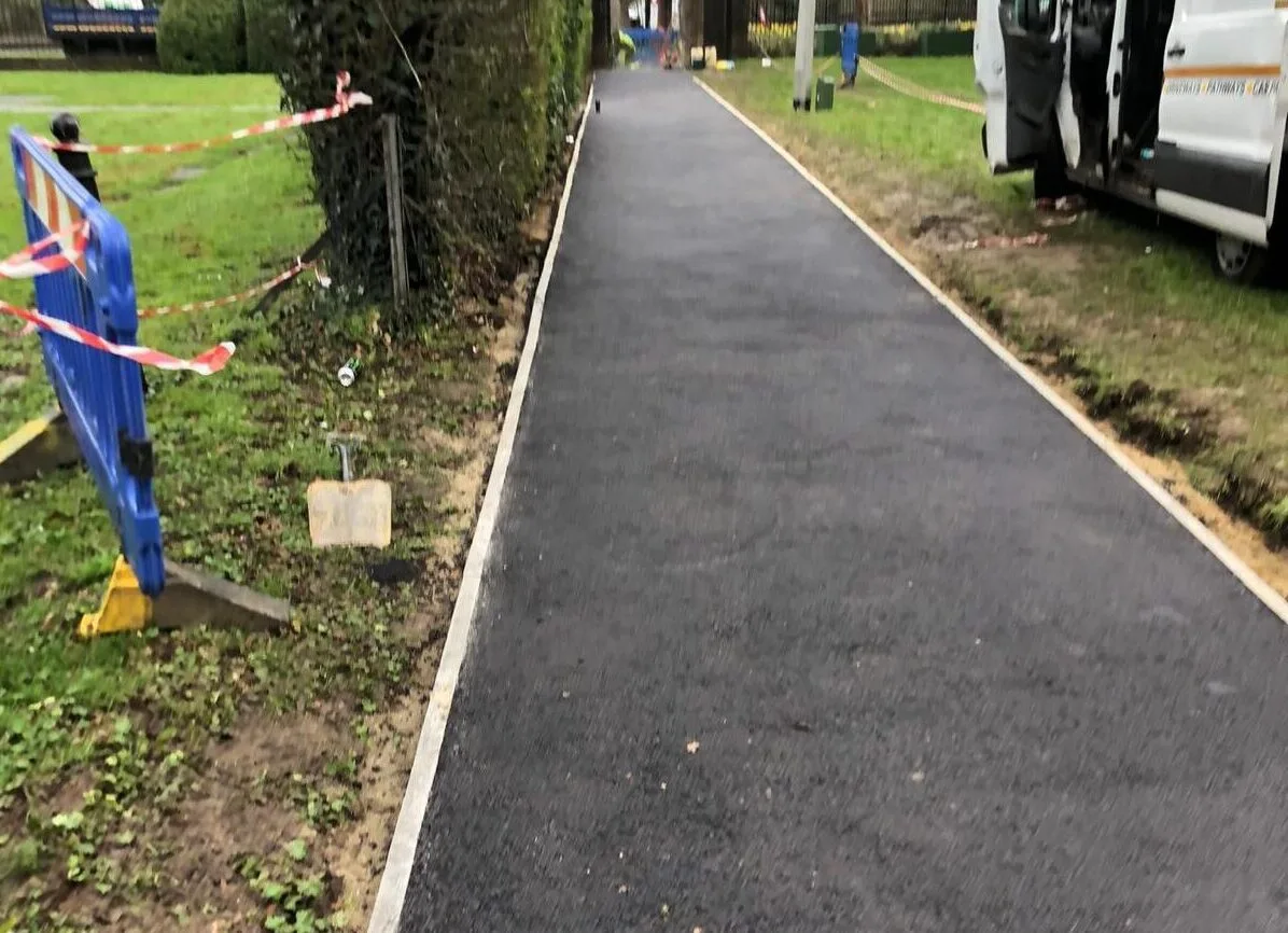 A tarmac pathway being laid through parkland