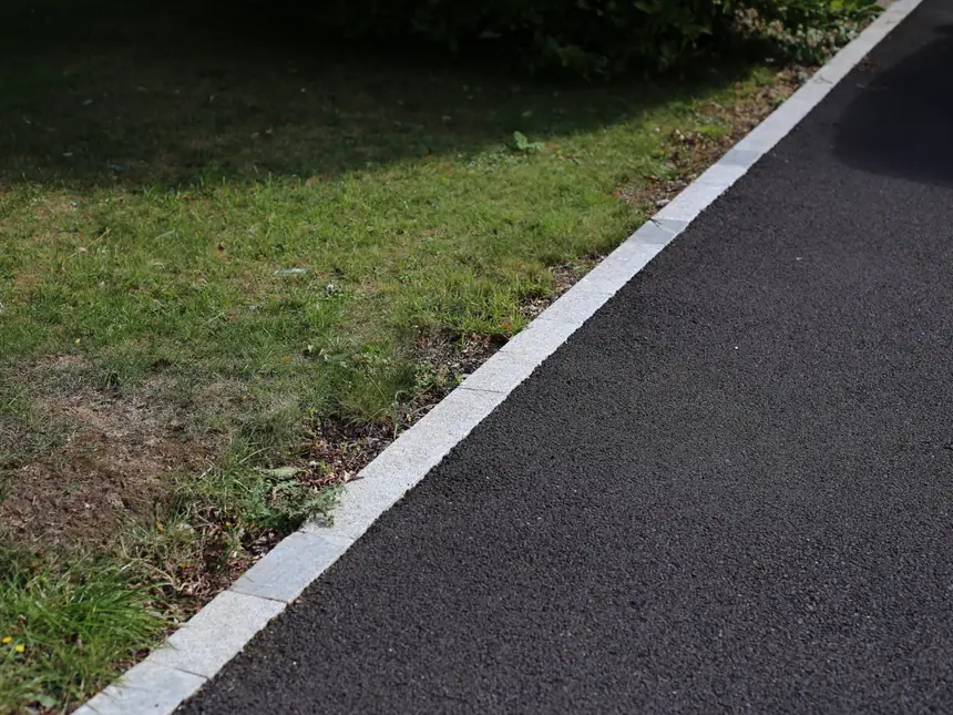 A kerbed path edge against a grass verge