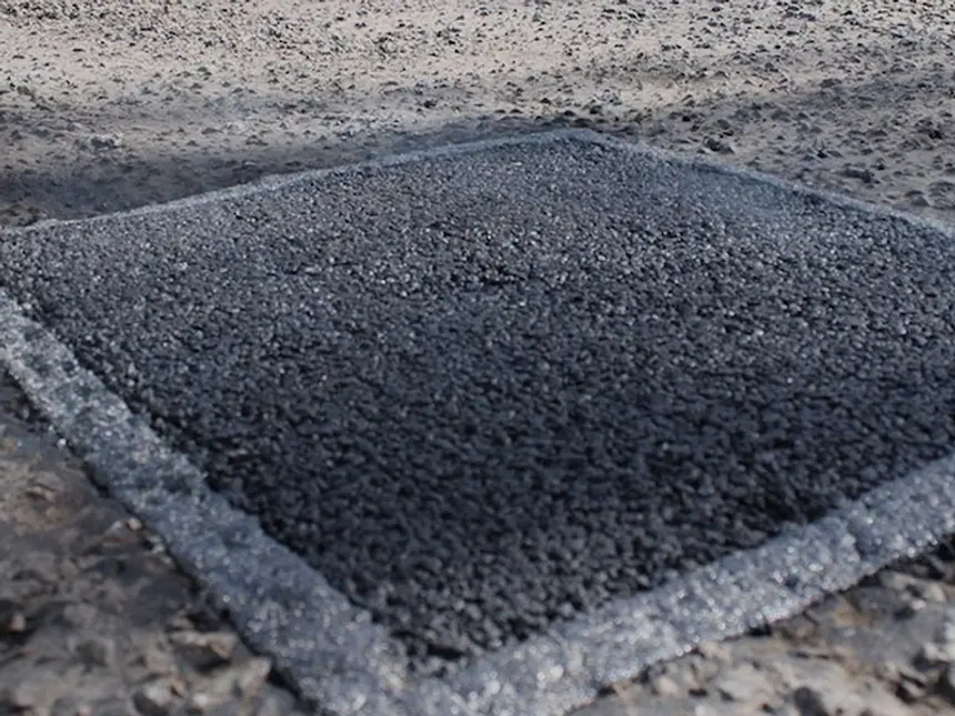 Hot asphalt being raked into a pothole