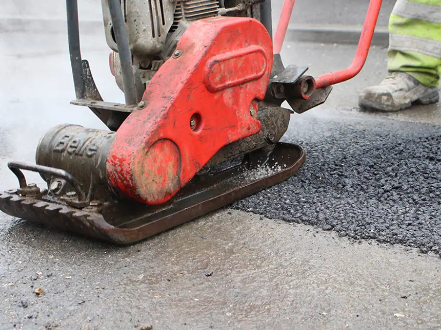 A completed asphalt patch over a filled pothole