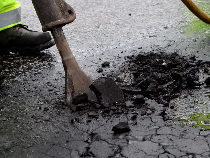 A plate compactor finishing a pothole repair