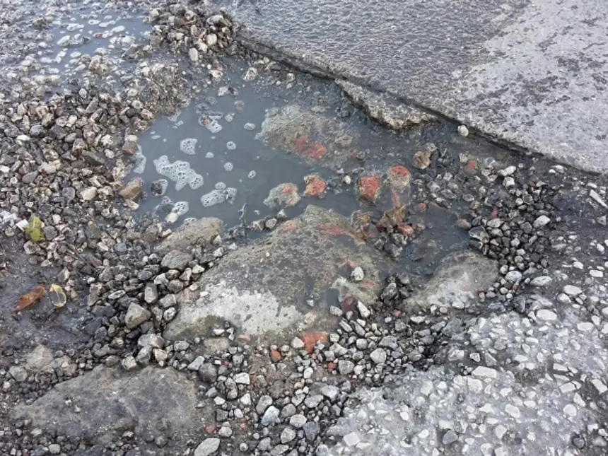 A pothole part-filled with loose stone