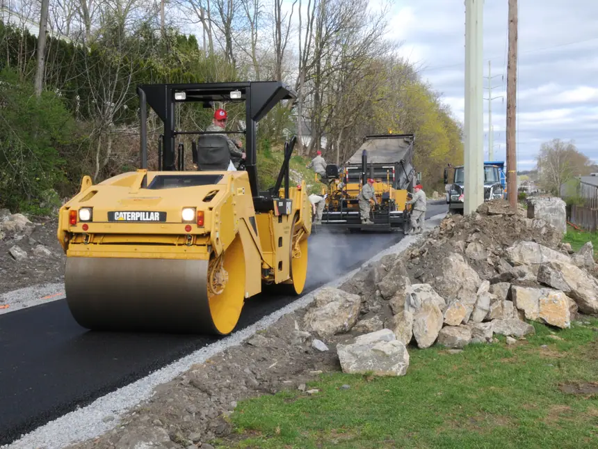 A roller and paver resurfacing a rural road