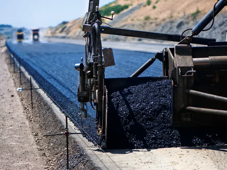 The screed of a paver laying an asphalt mat