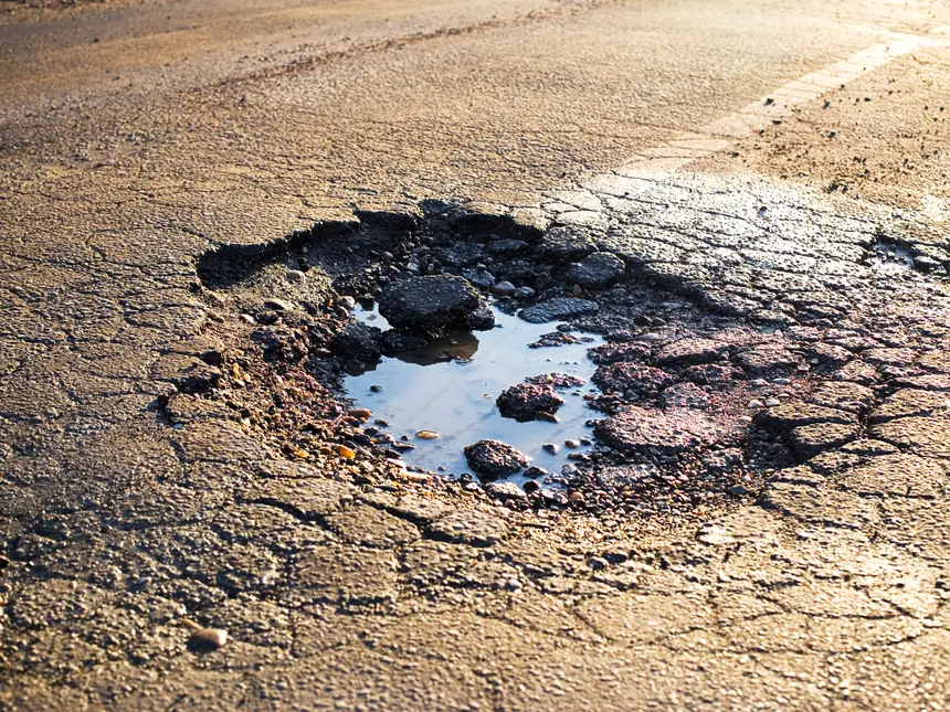 Broken asphalt at the edge of the carriageway