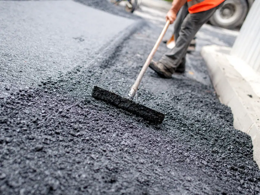 A contractor raking tarmac level