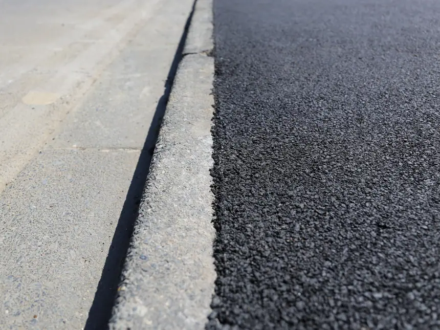 A tarmac edge detail against a concrete channel