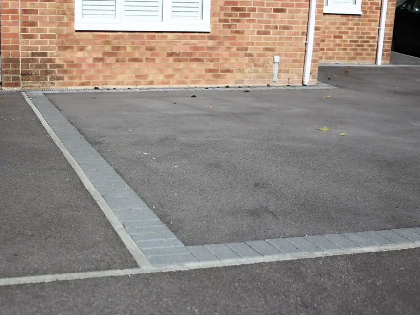 A tarmac driveway with a contrasting block band
