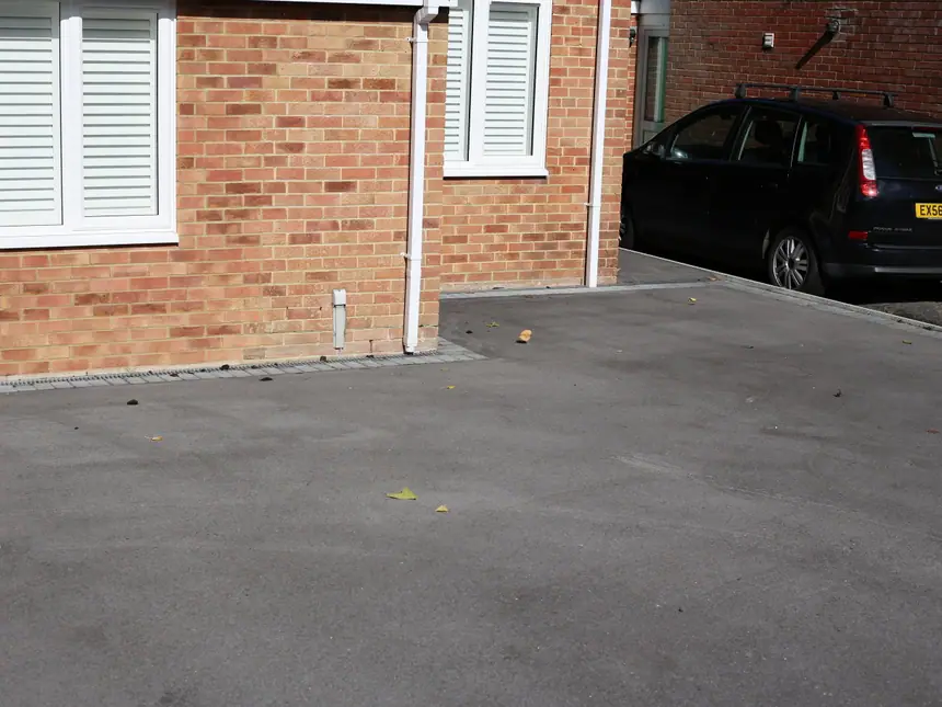 A finished tarmac driveway with a car parked on it