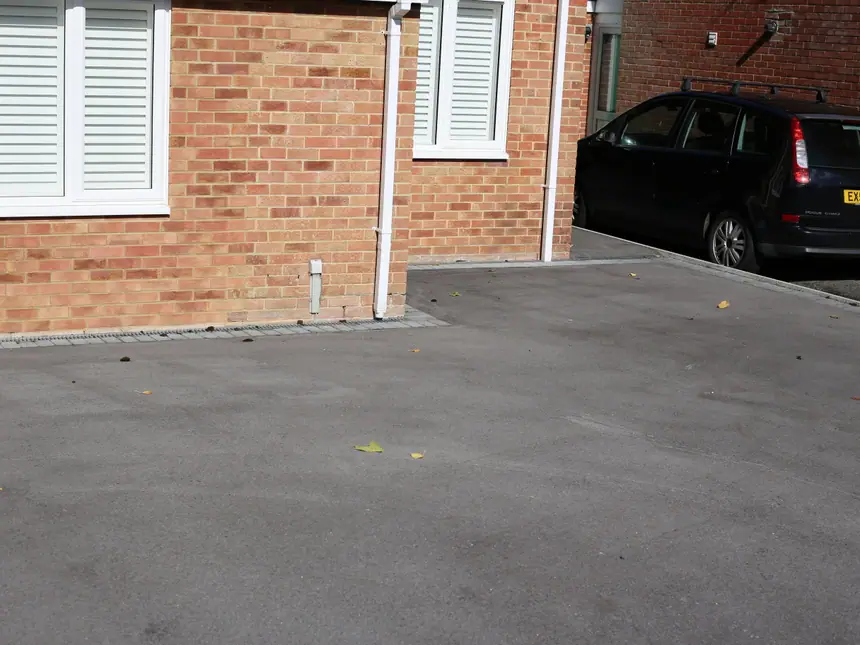 A tarmac driveway alongside a brick frontage