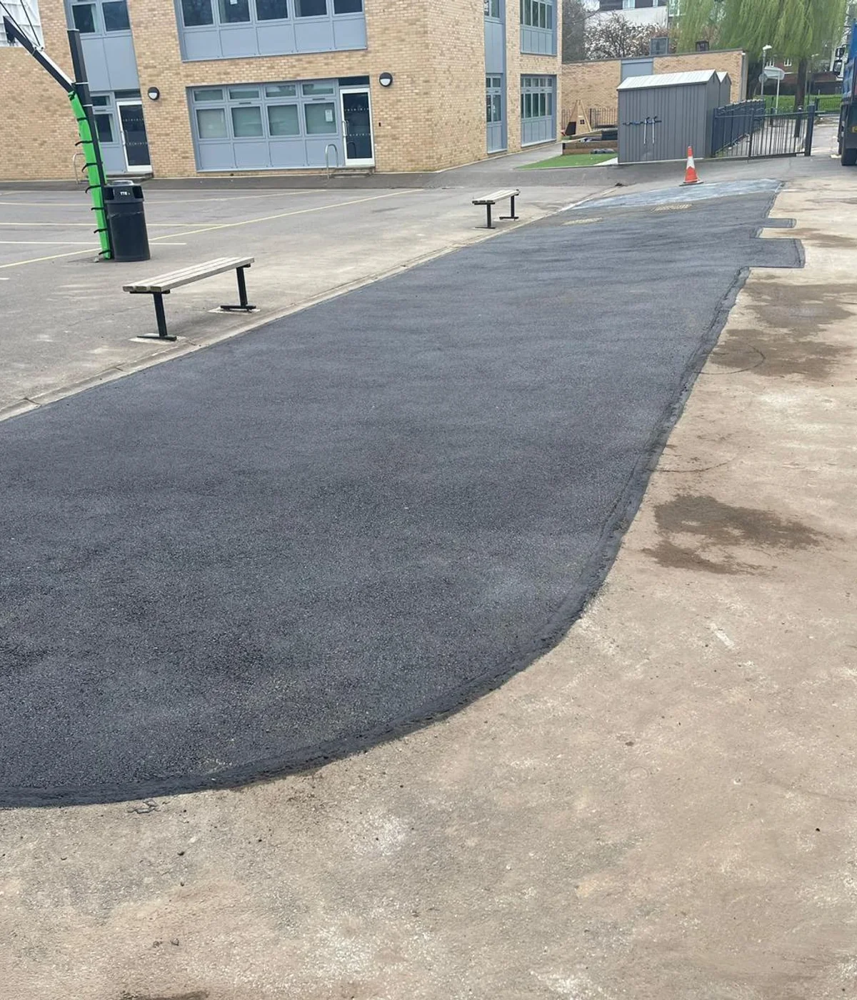 A school playground part-way through resurfacing, with plant on site